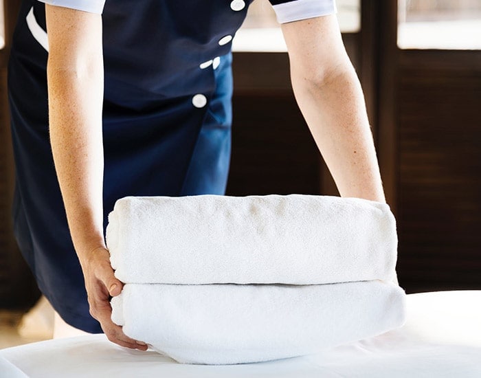 Server leaving clean towels on a bed