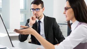 women pointing at computer while man looks at it