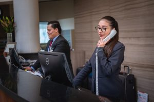 women on the phone looking at computer, man in background looking at computer