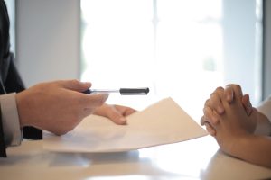 a person giving a pen to another person sitting in front of them