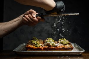 private chef grating some cheese onto a dish made for a customer