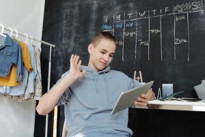 kid using his ipad to take online classes while homeschooling