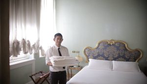 a butler about to put sheets on a bed