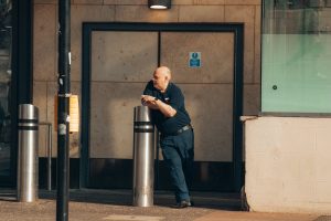 A security guard smoking while leaning on a column