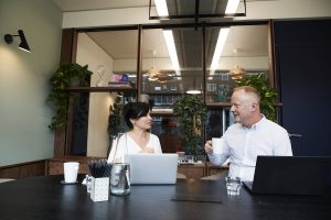 A man and a woman sitting on a desk talking