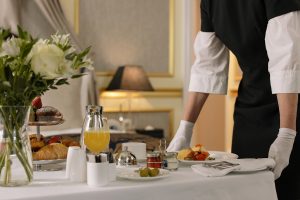 A butler getting a table of food ready for their employer