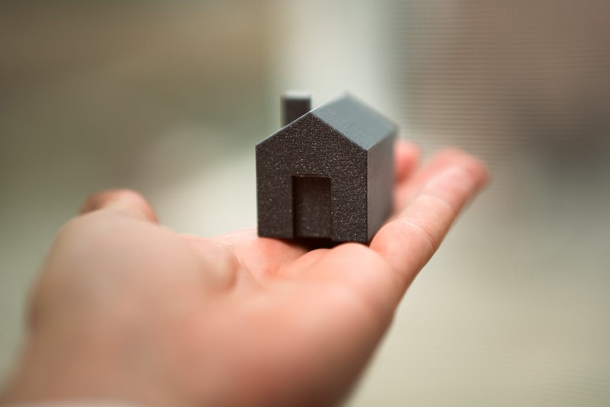 A person holding a mini house in their palm