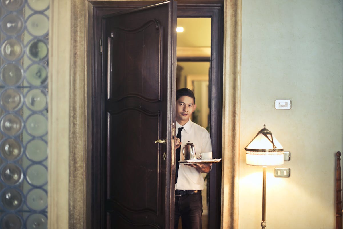 A butler entering a room with some drinks