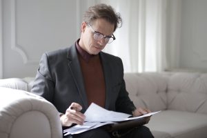 A man looking at a bunch of papers on a couch
