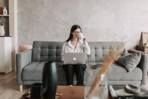 A lady sitting on a couch drinking out of a mug