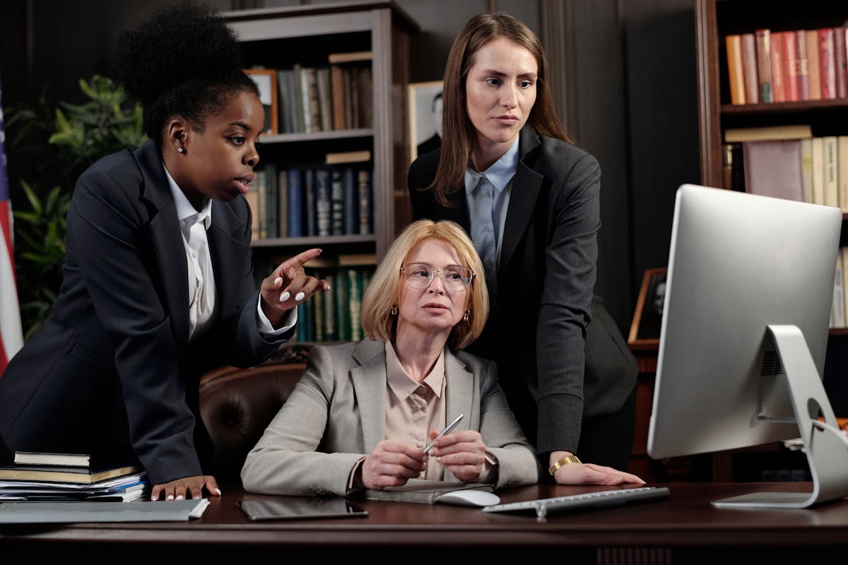 A bunch of office workers gathered around a computer screen