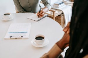 A person writing down notes with someone across the table