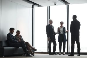 A bunch of office workers talking next to a window