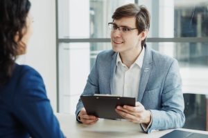 An HR Manager talking to an employee while holding a clipboard