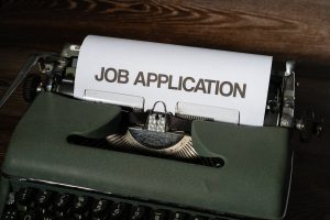 A typewriter with a paper that says job application