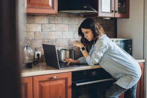 A woman looking at a laptop in a kitchen