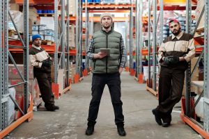 A bunch of people standing in a warehouse full of random items