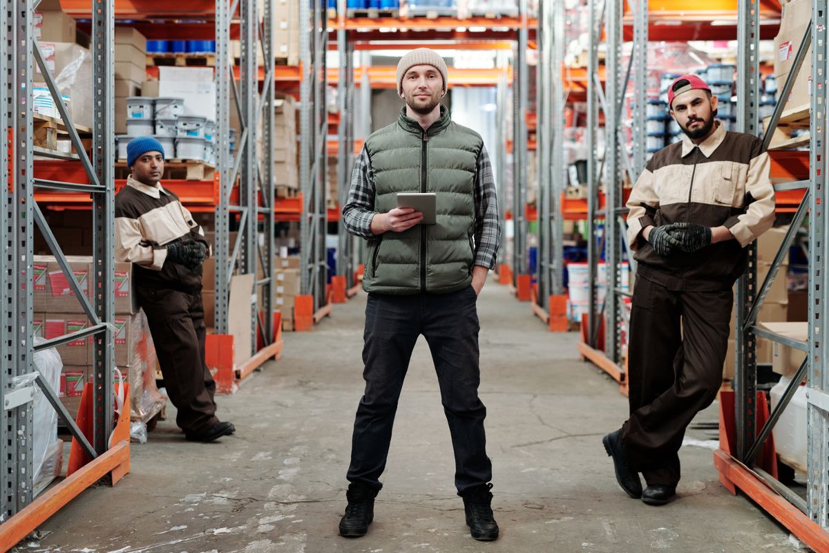A bunch of people standing in a warehouse full of random items