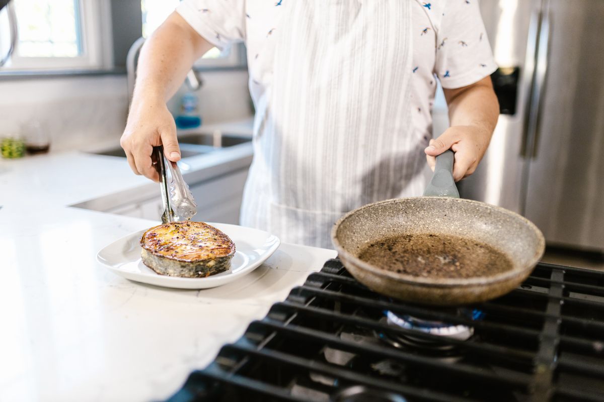 A professional cook placing a slab of cooked meat on a plate